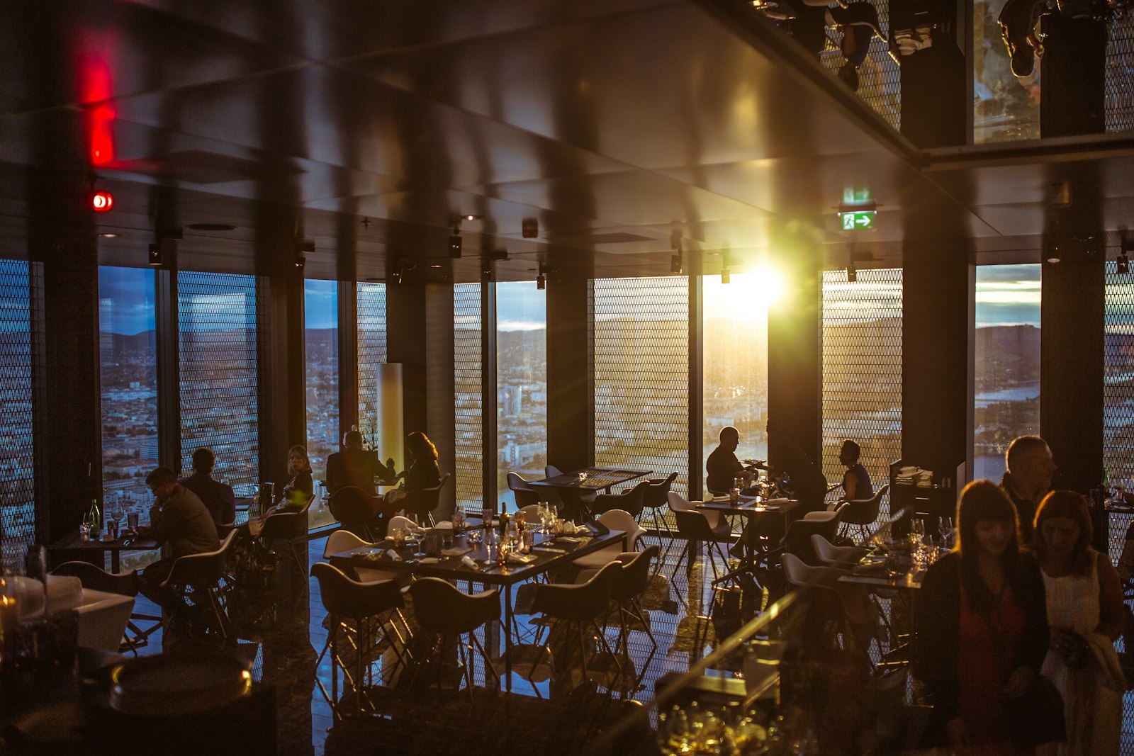 Des clients attablés dans la salle d’un restaurant, à la lumière dorée du soir